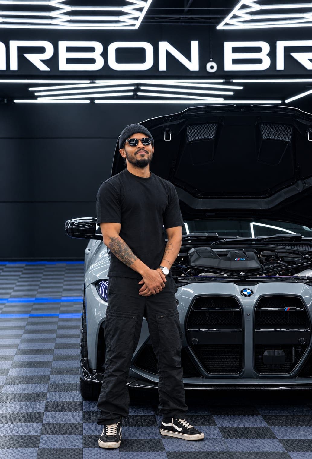 Standing before a BMW M4 with its bonnet up under the Carbon Bros lights