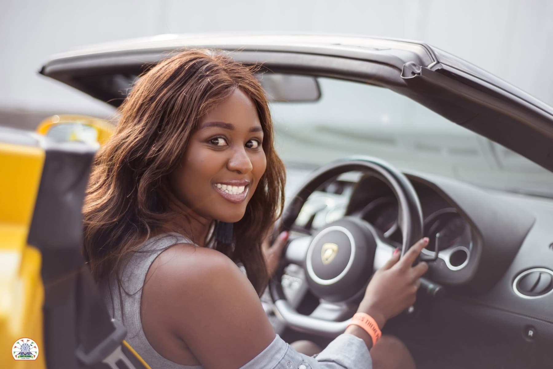 Smiling from the driver's seat of a yellow Lamborghini