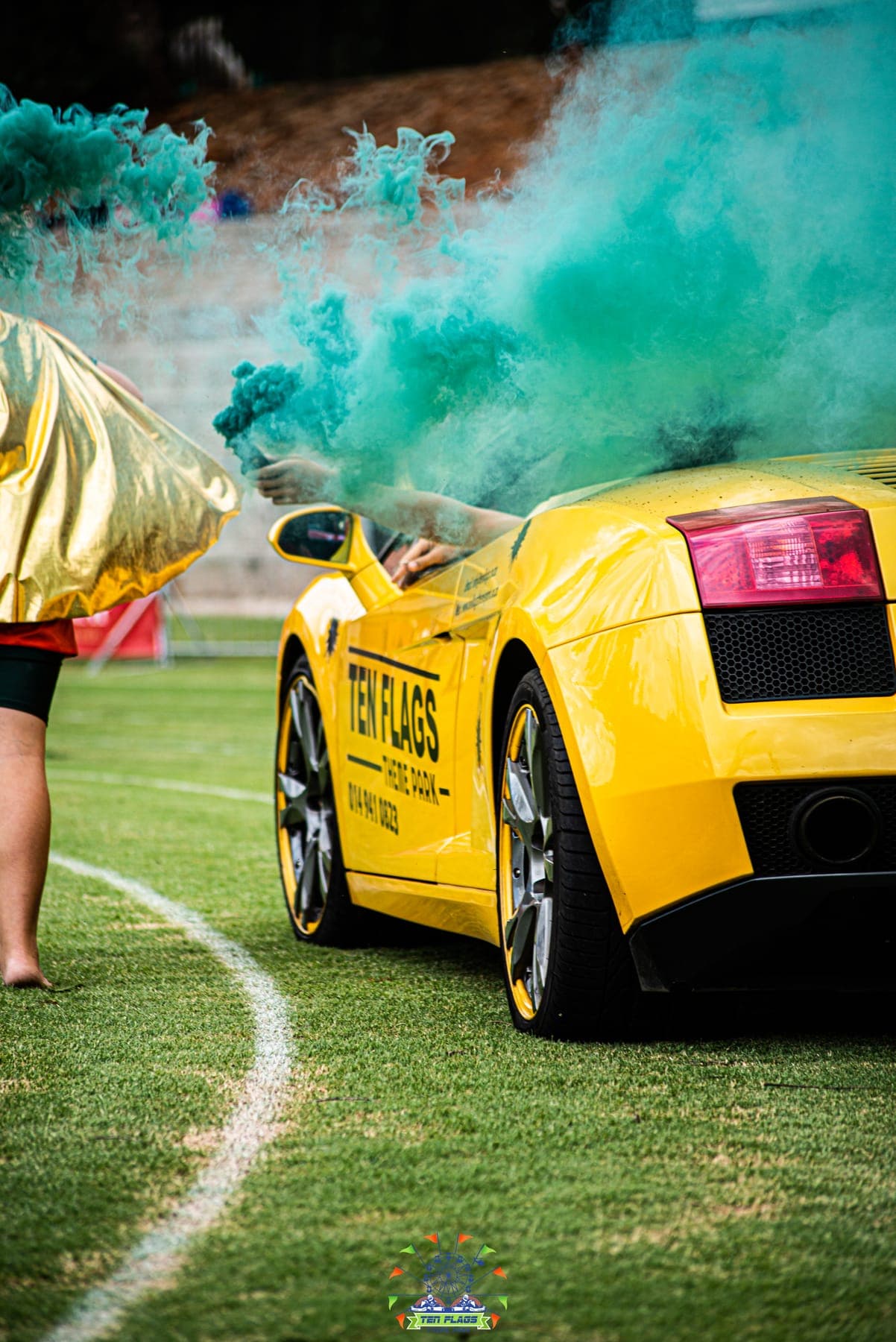 Yellow Lamborghini on a sports field as teal smoke rises