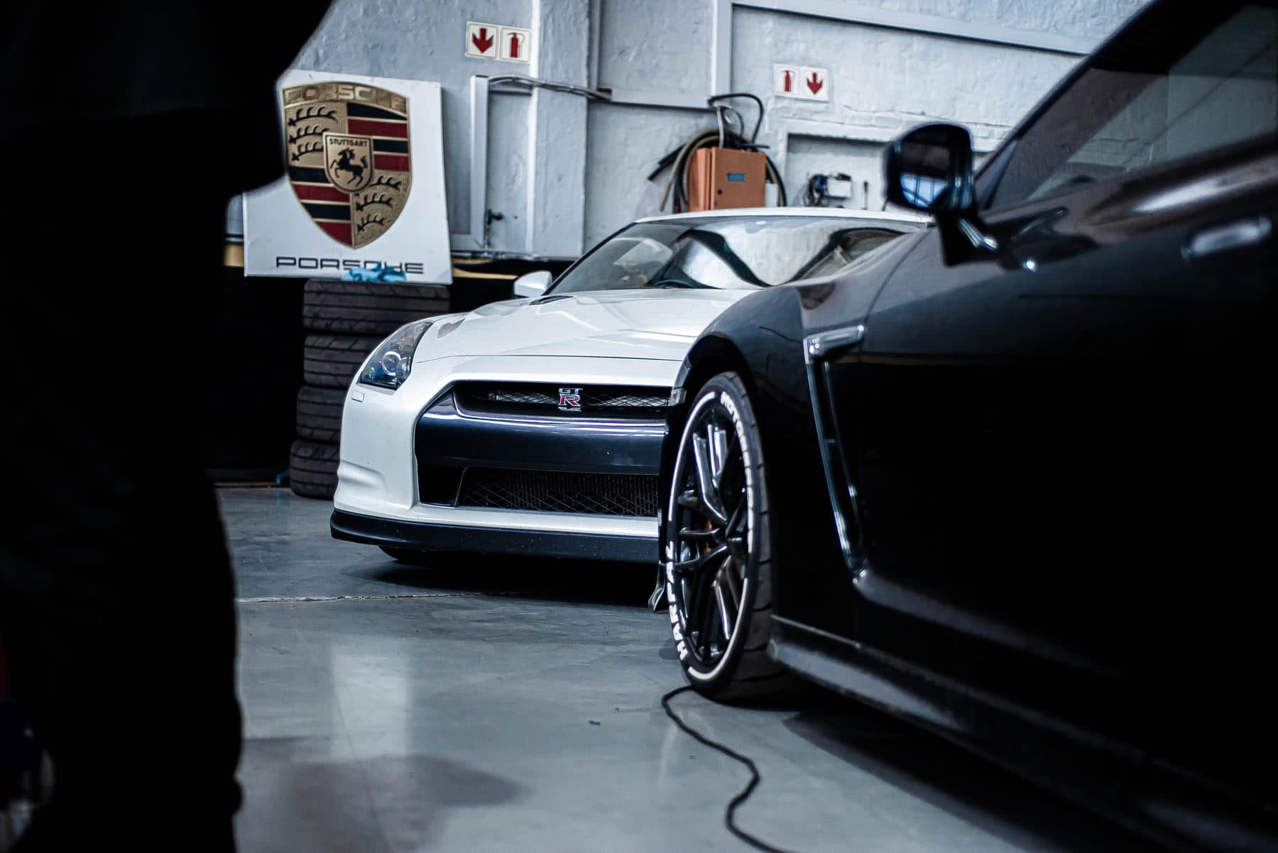 Black Porsche and a white GT-R in the workshop