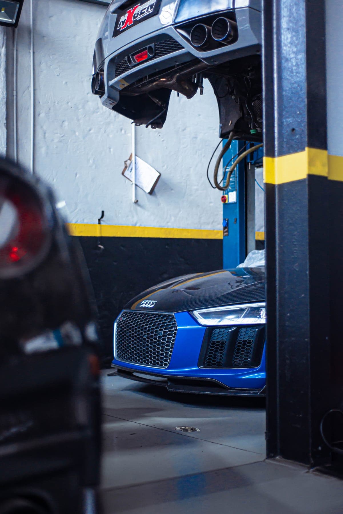 Blue Audi R8 under a workshop lift