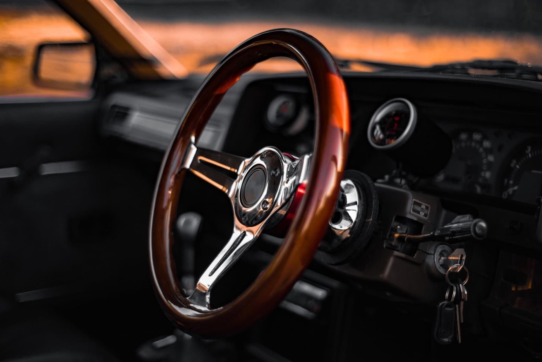 Wooden steering wheel and chrome spokes in amber light