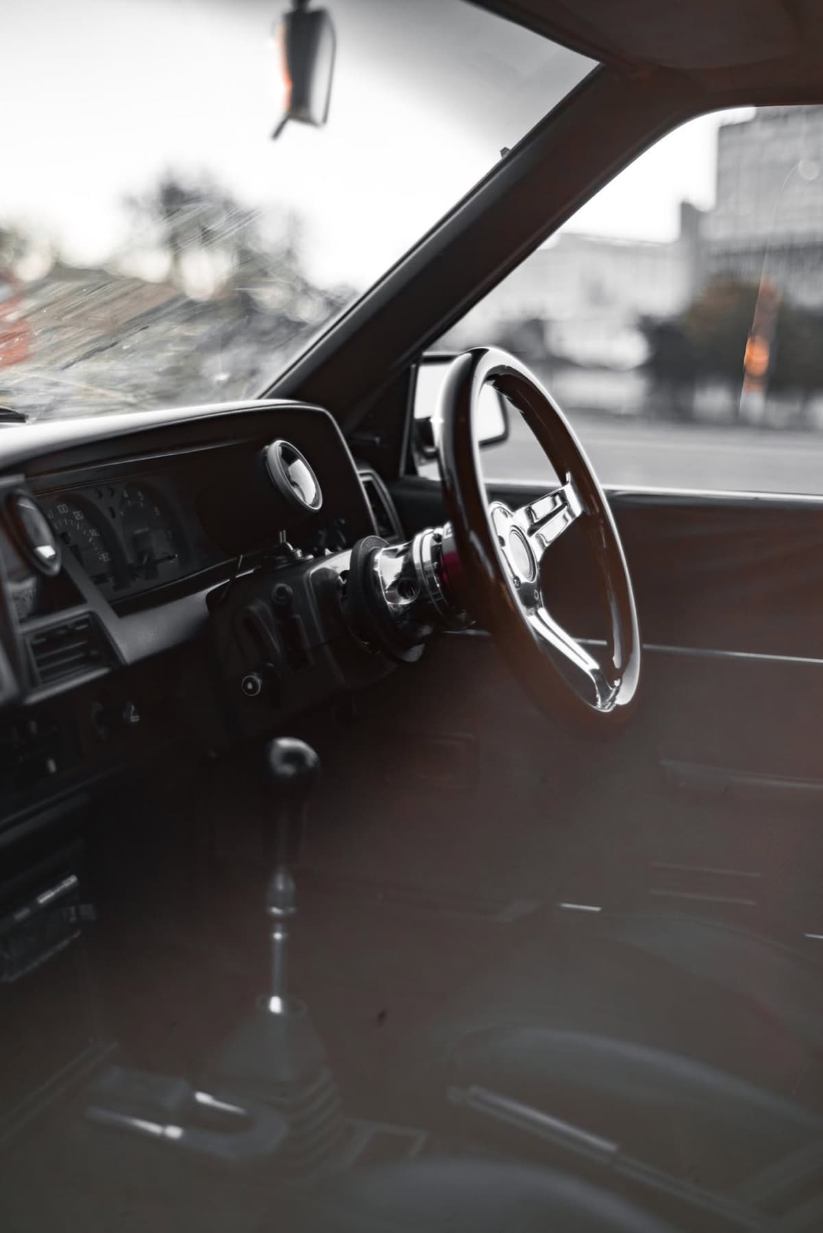 Wooden steering wheel in a classic cabin, the city beyond the glass