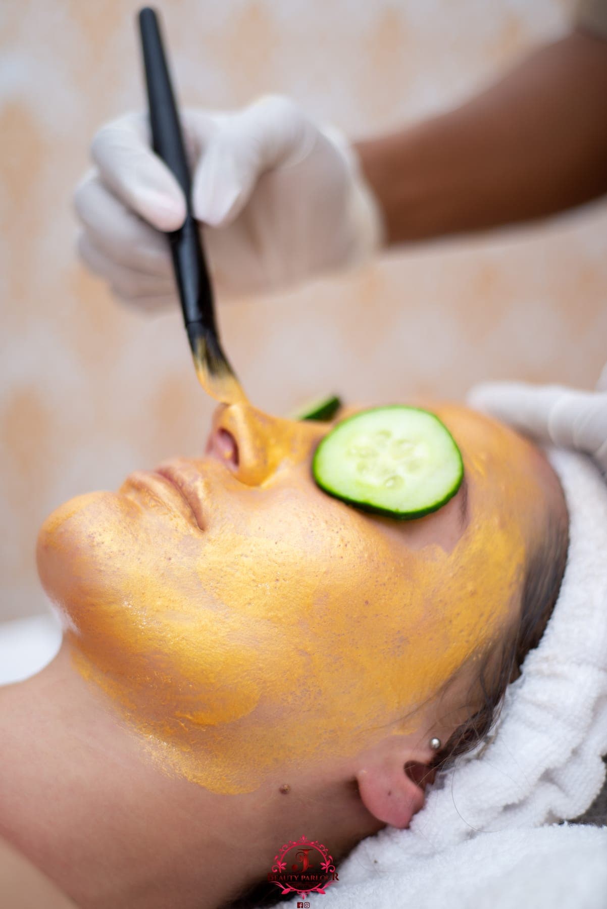 Gold face mask brushed on, cucumber slices over the eyes
