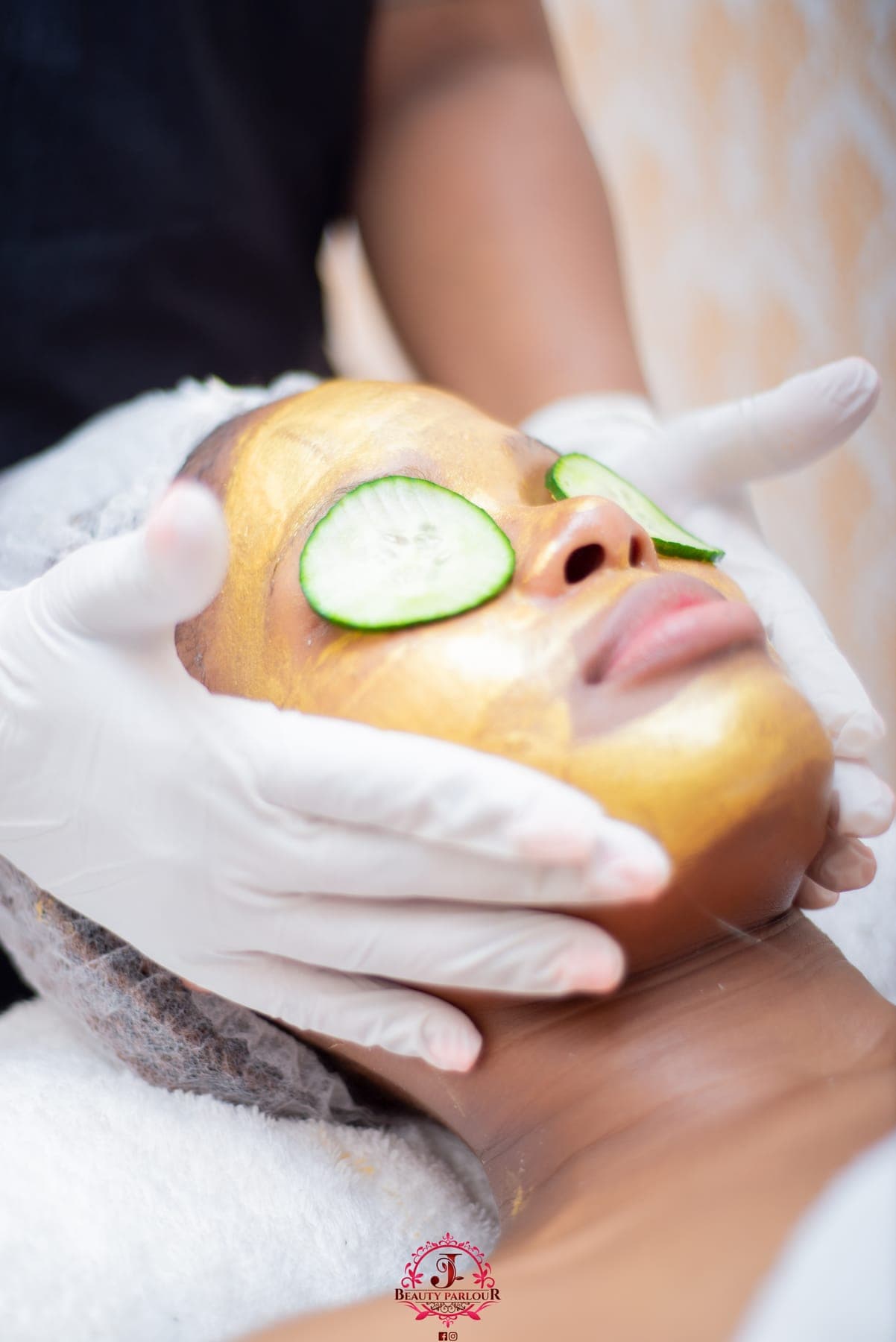 Gloved hands smoothing a gold face mask