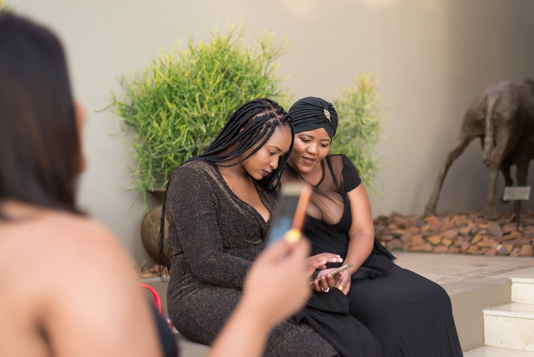 Two guests in black sharing a phone on the steps