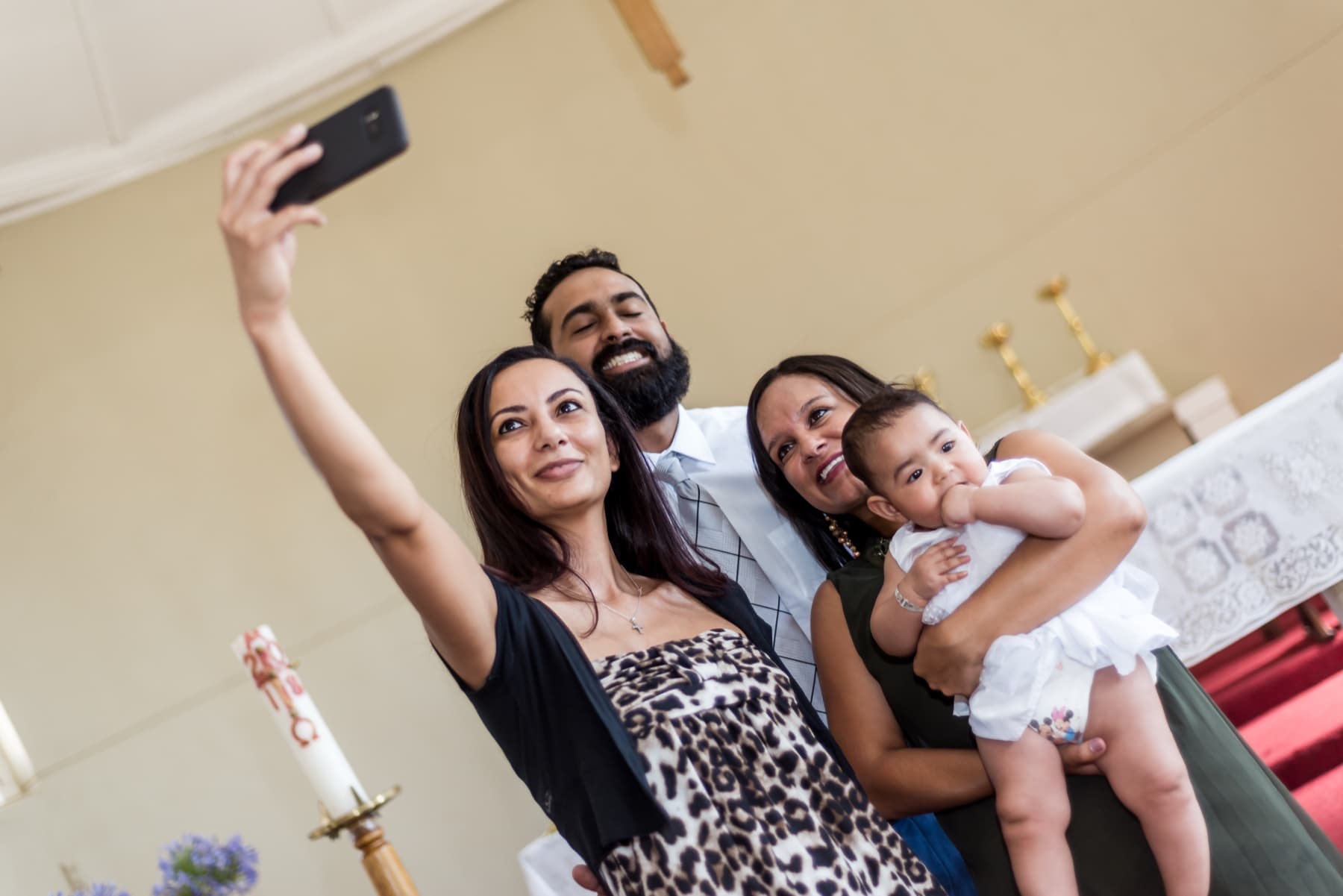 Family selfie beneath the chapel cross at a christening