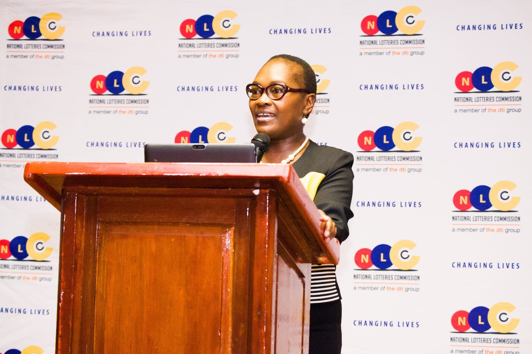 Speaker at a podium in front of the National Lotteries Commission backdrop