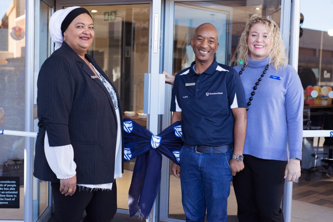 The branch team at the new doors beside the blue ribbon