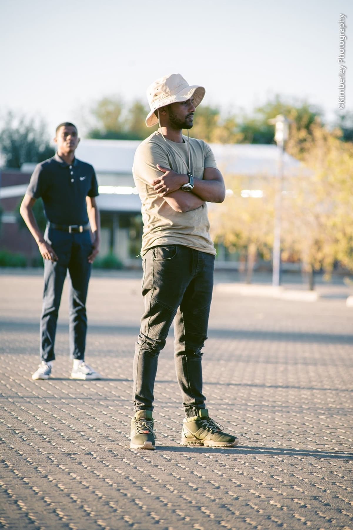 Bucket hat, checking a watch on paved ground