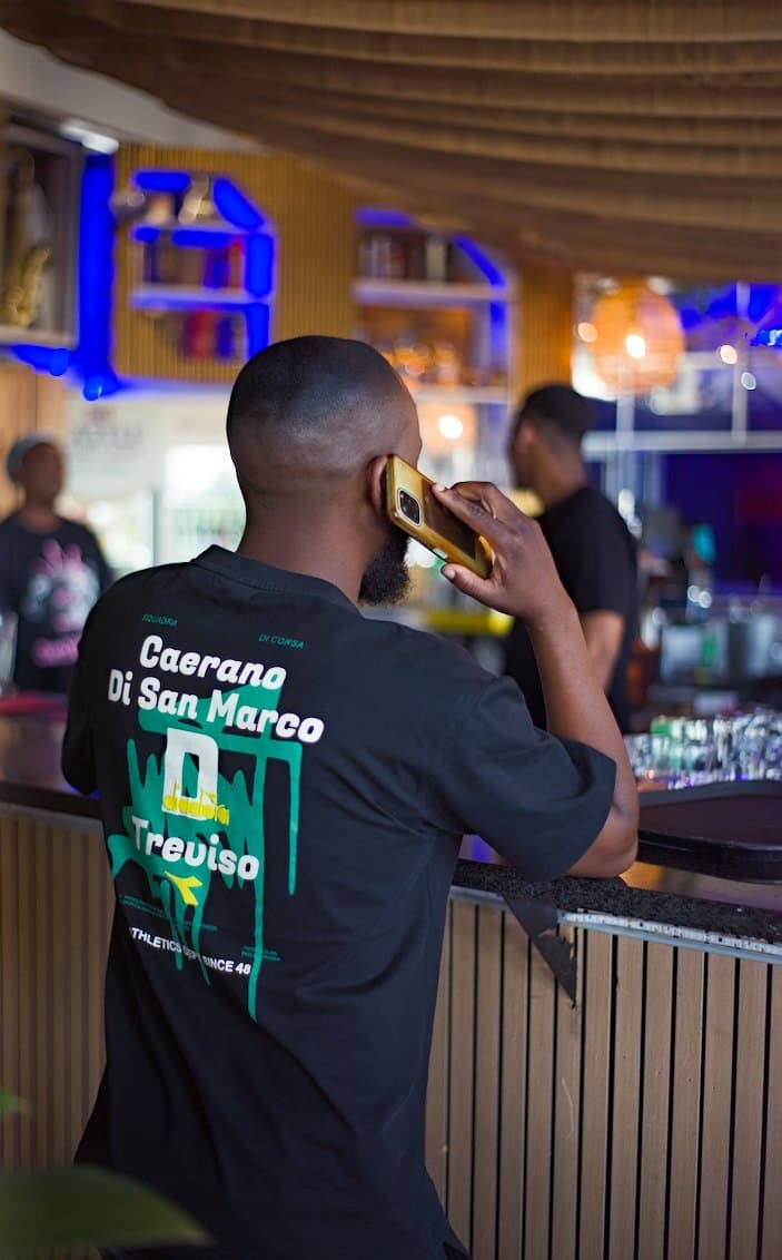 On the phone at the bar in a Caerano Di San Marco tee