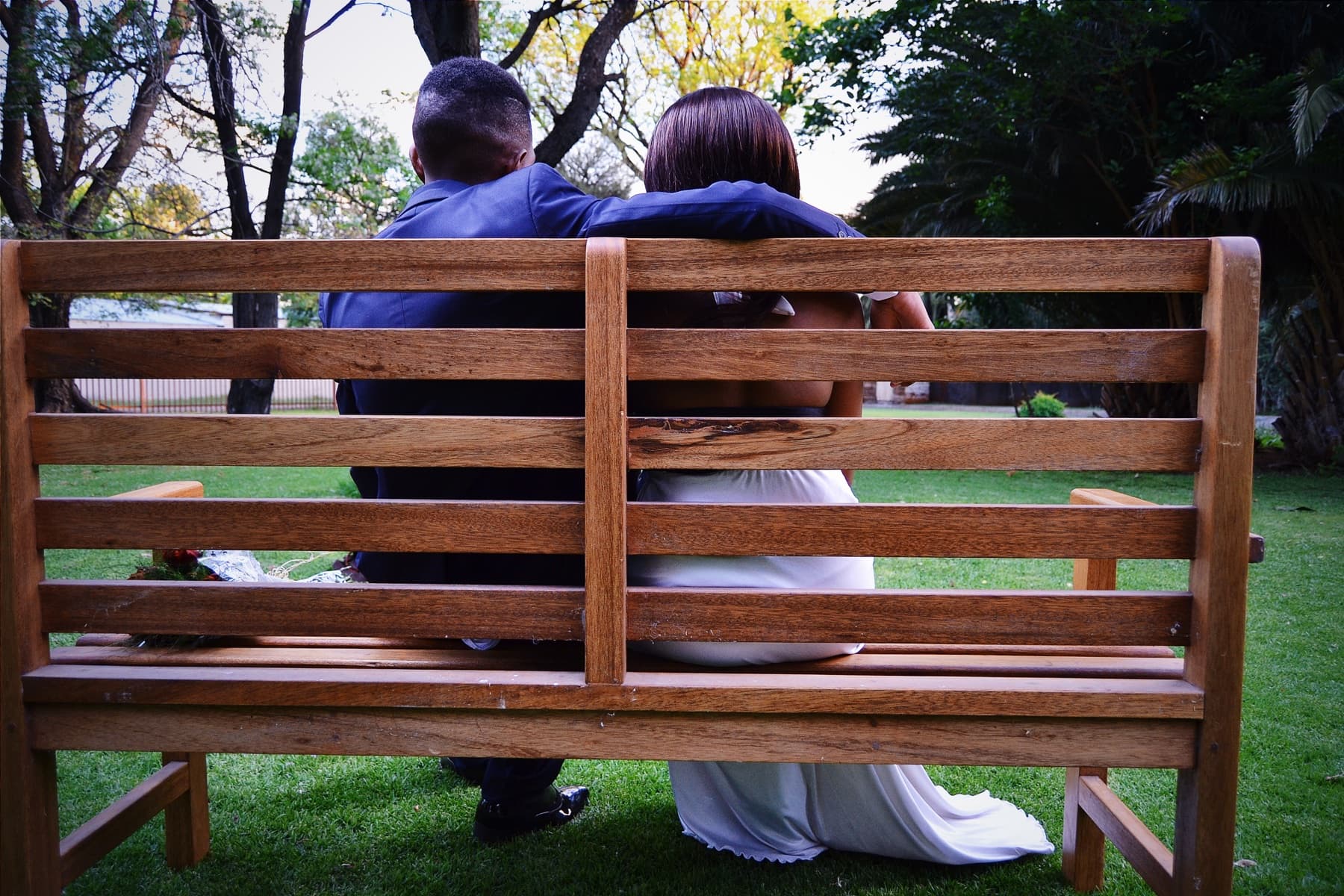 Matric dance couple from behind on a wooden bench
