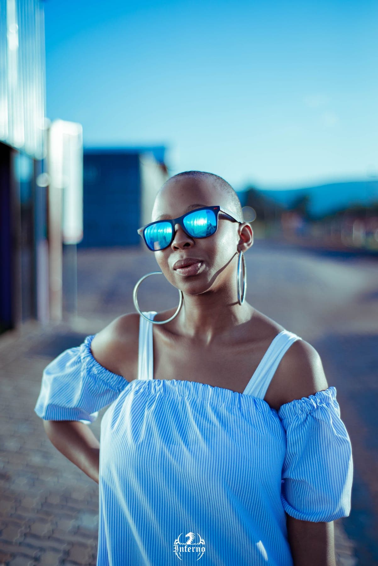 Woman in an off-shoulder blue top and mirrored sunglasses