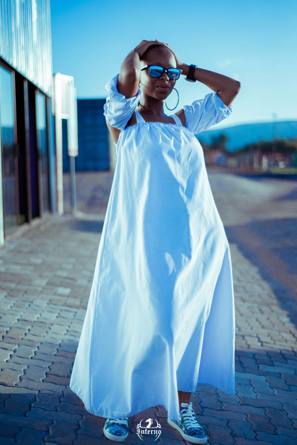 Woman in a long white dress and sunglasses on a paved street