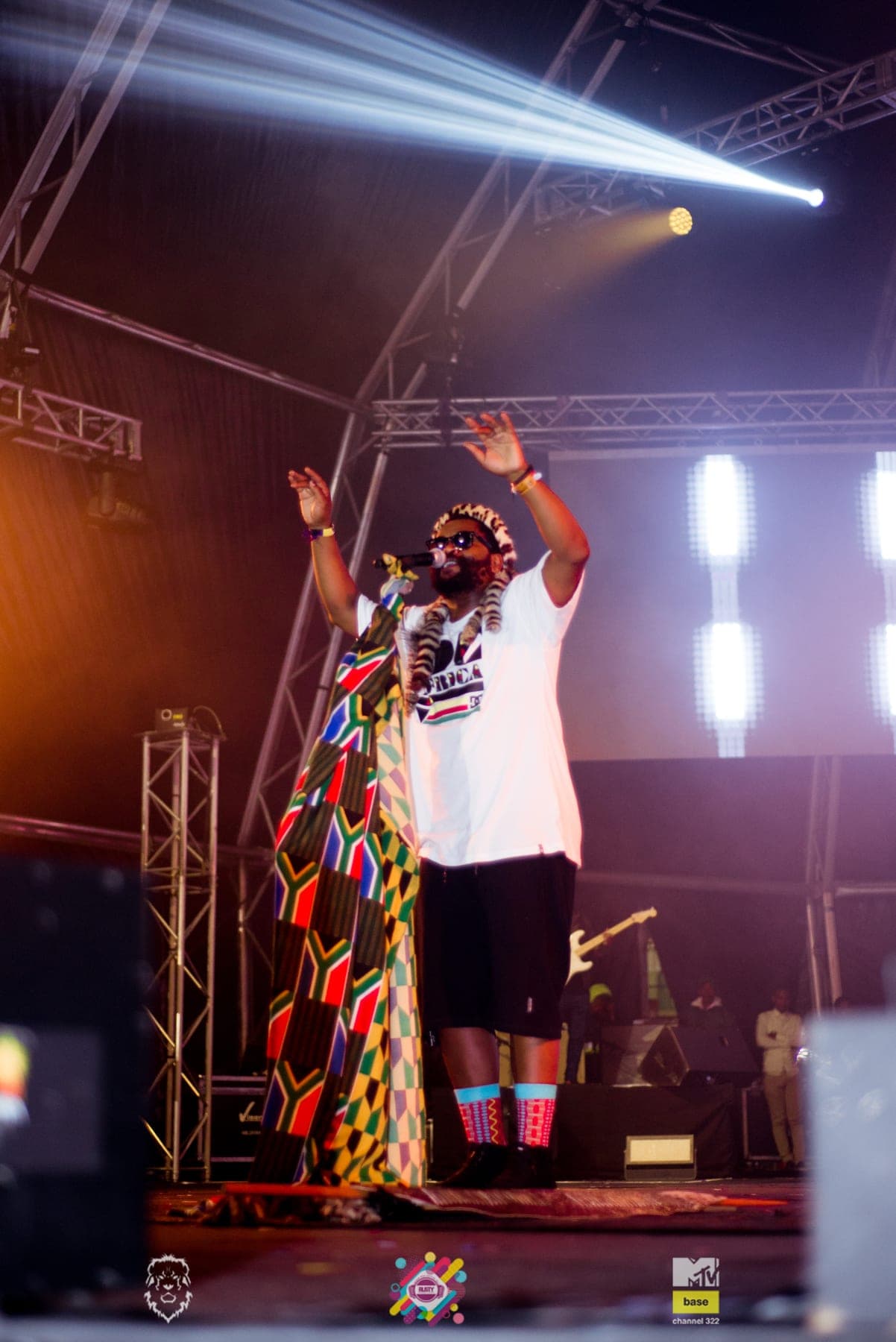 Both arms up in a patchwork outfit under the beams