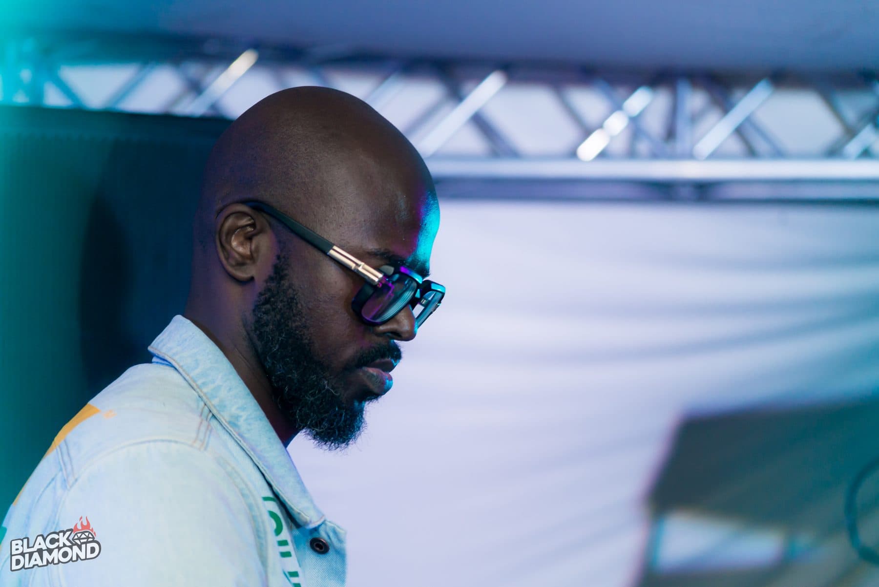 DJ in dark glasses at the decks, lit blue