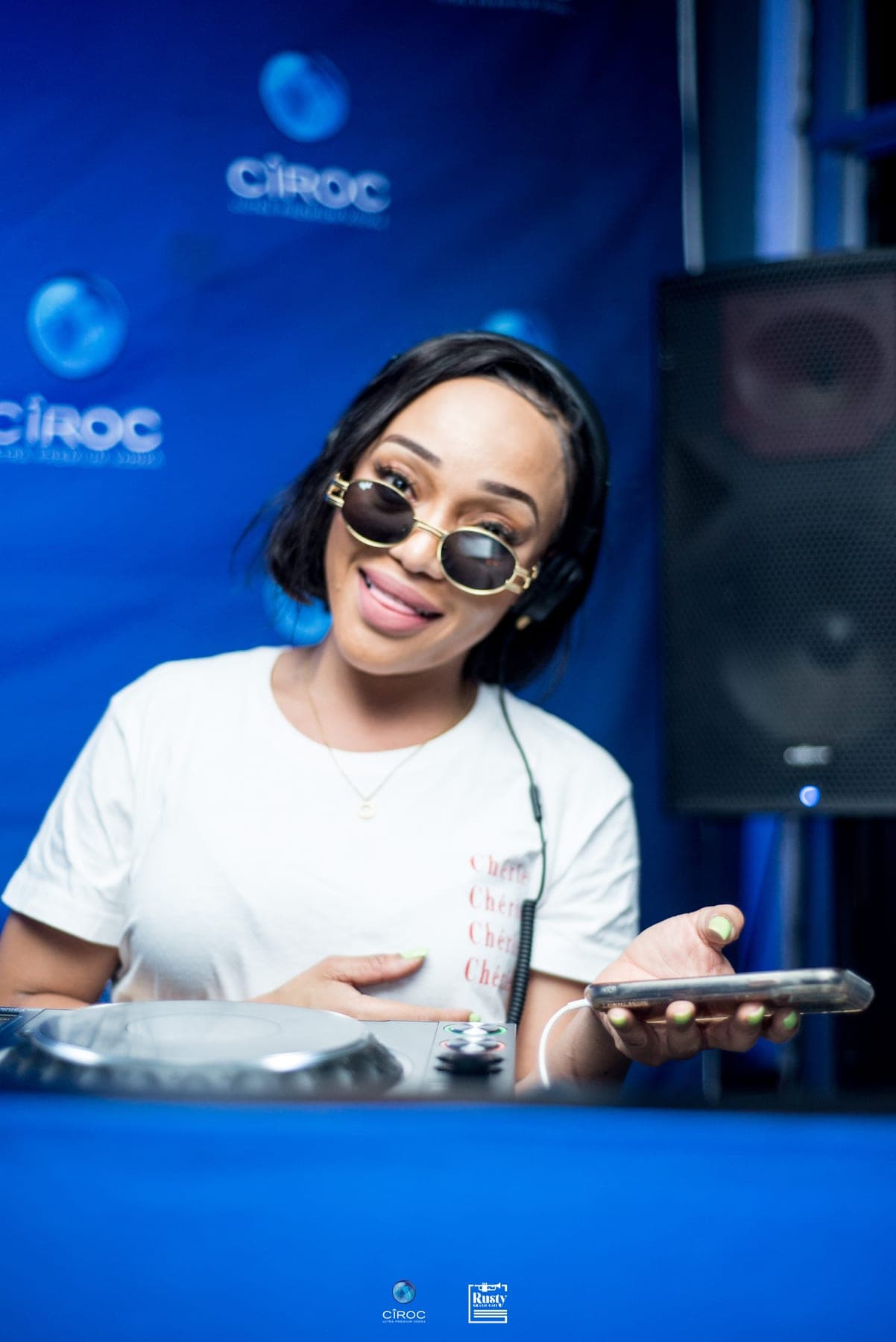 Smiling in sunglasses at a branded DJ booth