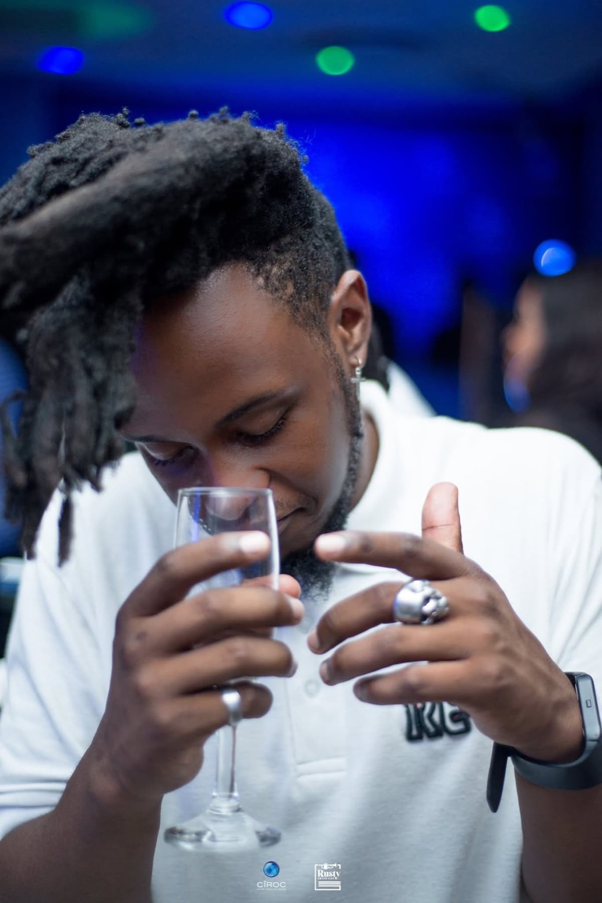 Dreads over a champagne flute, skull ring, blue wash