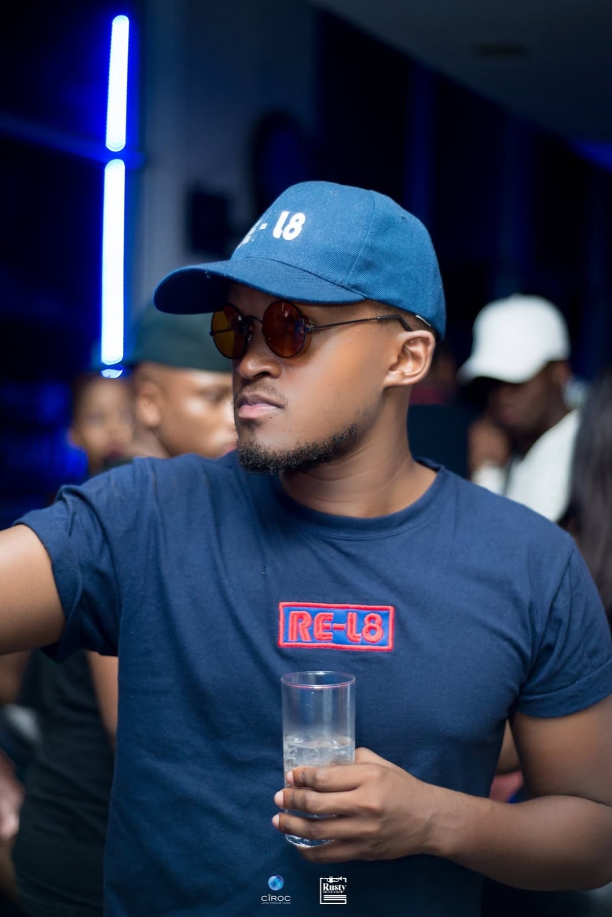 Round shades and a RE-L8 cap, glass in hand, lit blue