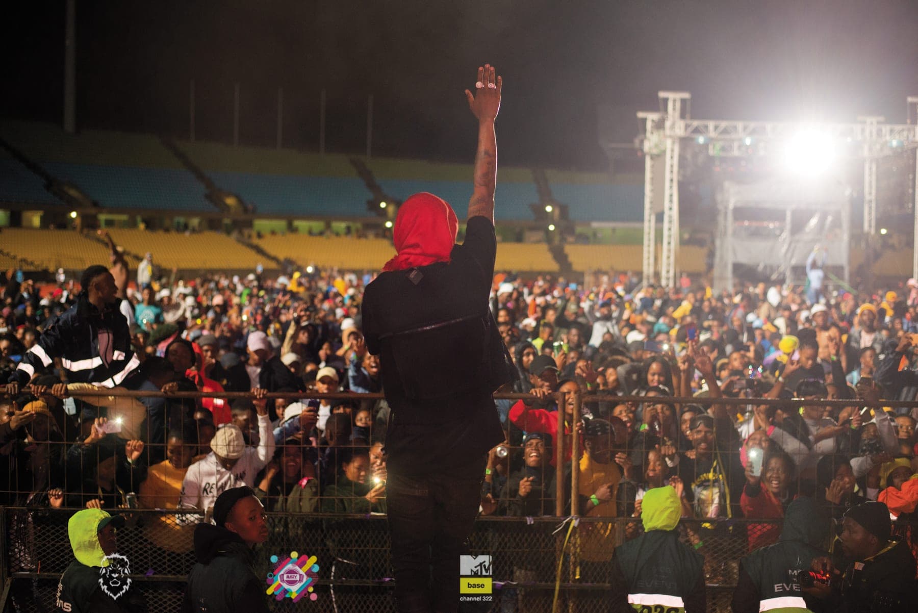 Performer with an arm raised over a packed stadium crowd