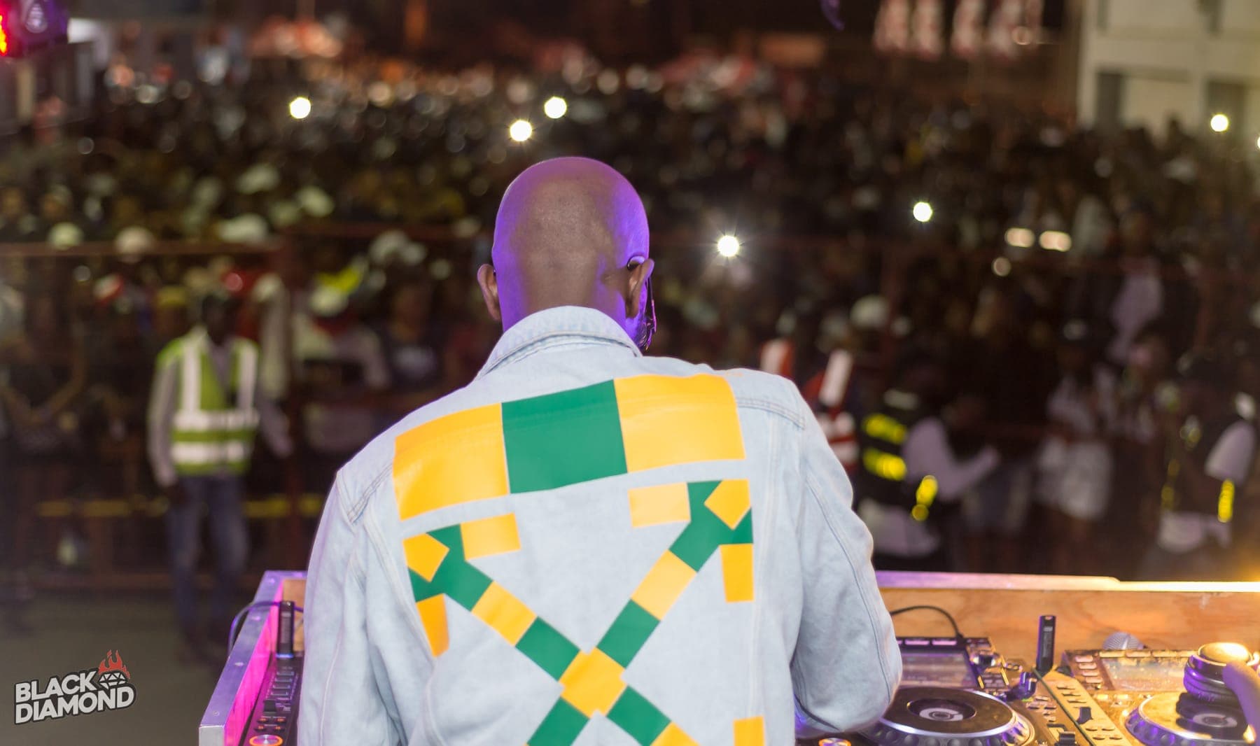 View from behind the DJ over a crowd holding up phones