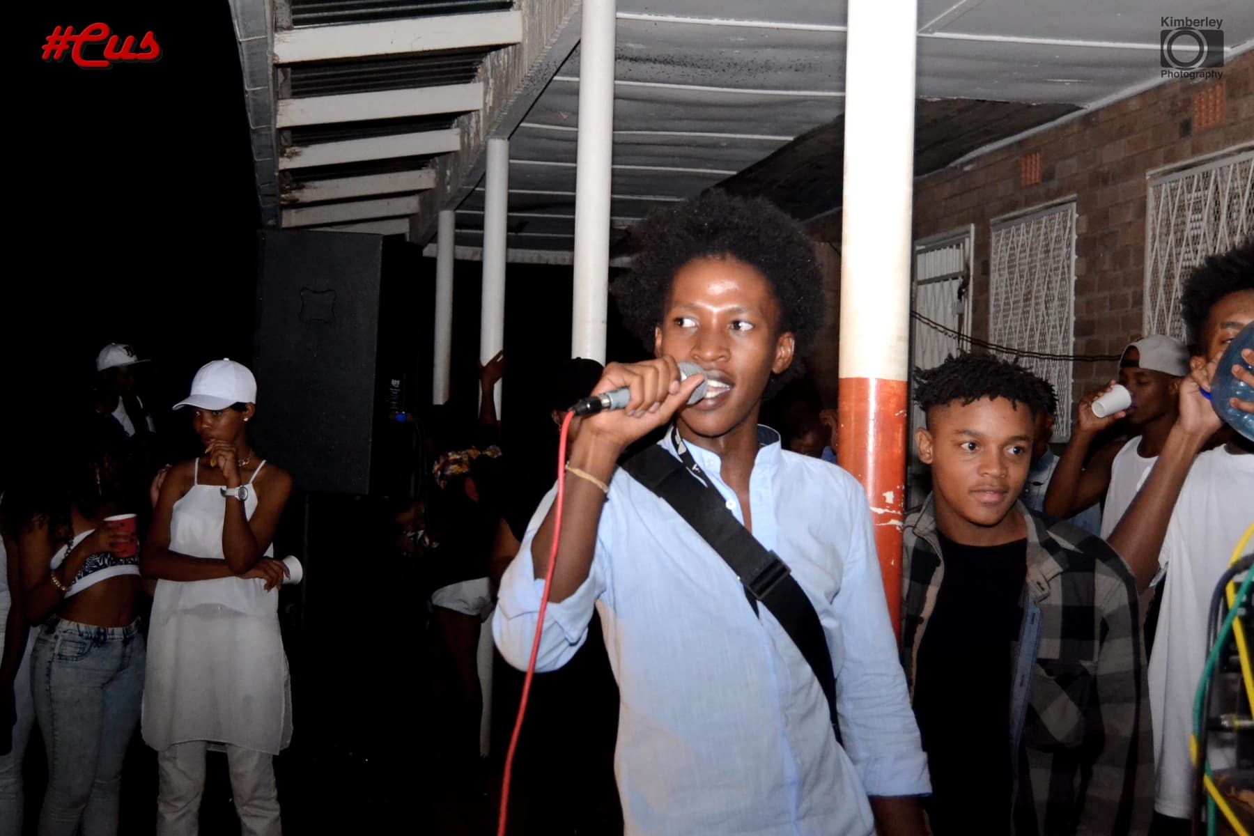 Rapper in a blue shirt on the mic under the walkway at #Cus
