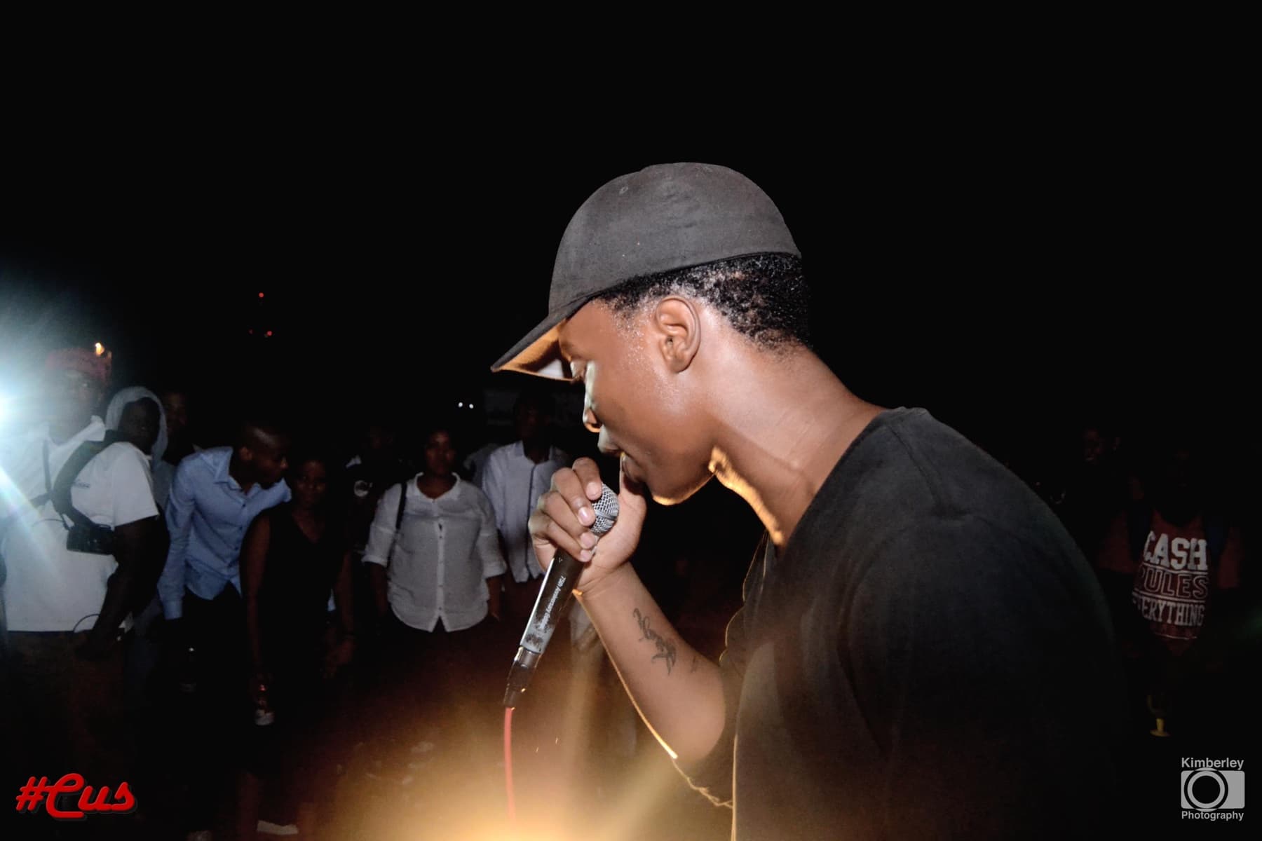 Rapper in a leather cap on the mic, camera flash behind him