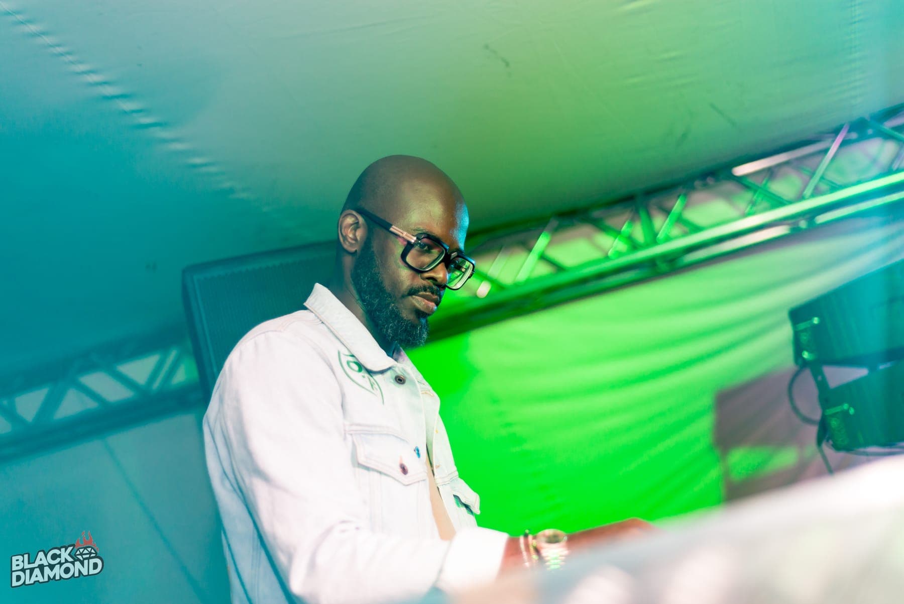 DJ in glasses and a denim jacket lit green