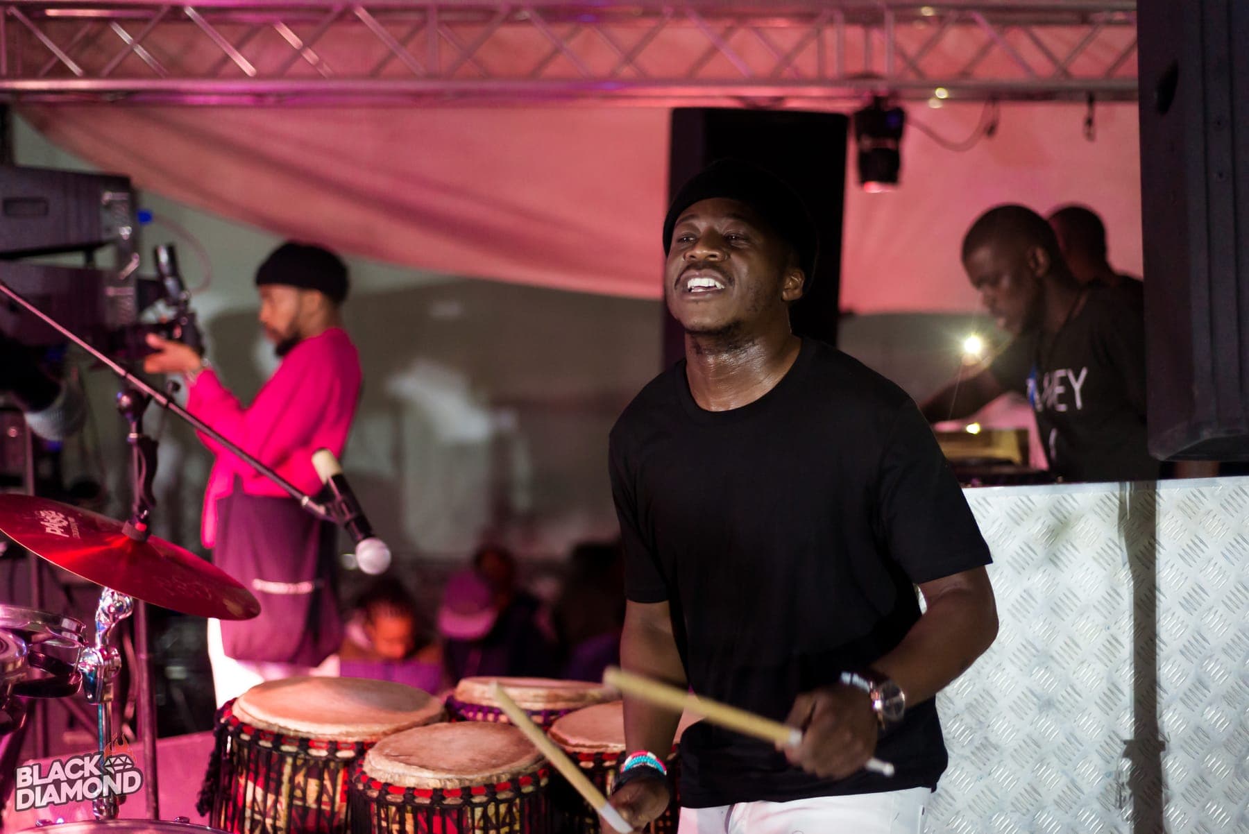 Percussionist laughing behind congas under pink light