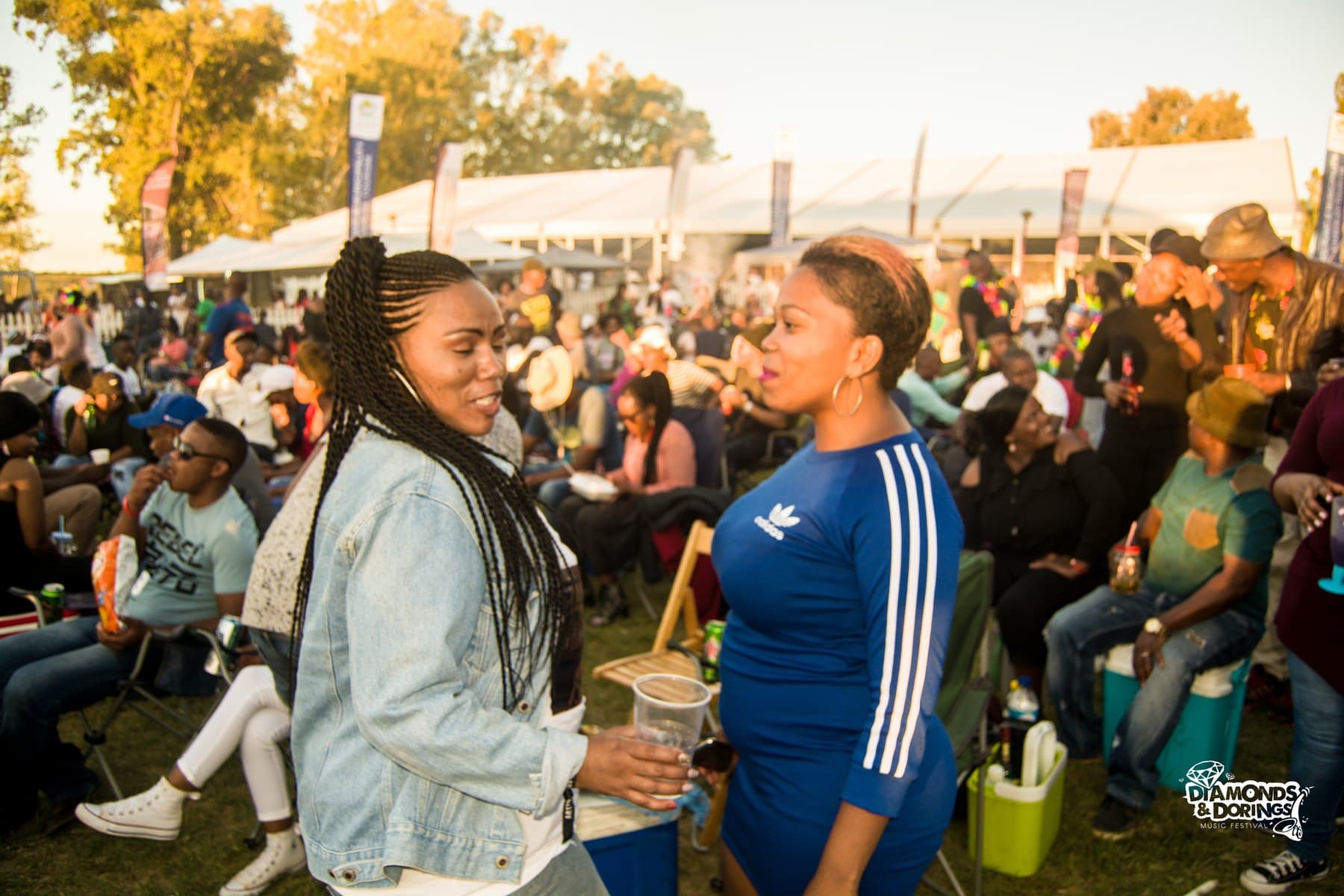 Two friends talking in a sunlit festival crowd