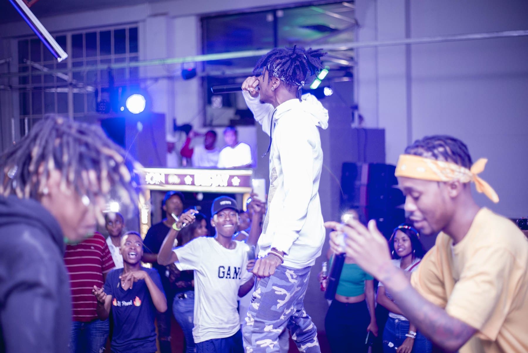Rapper in a white hoodie over a crowd washed in blue