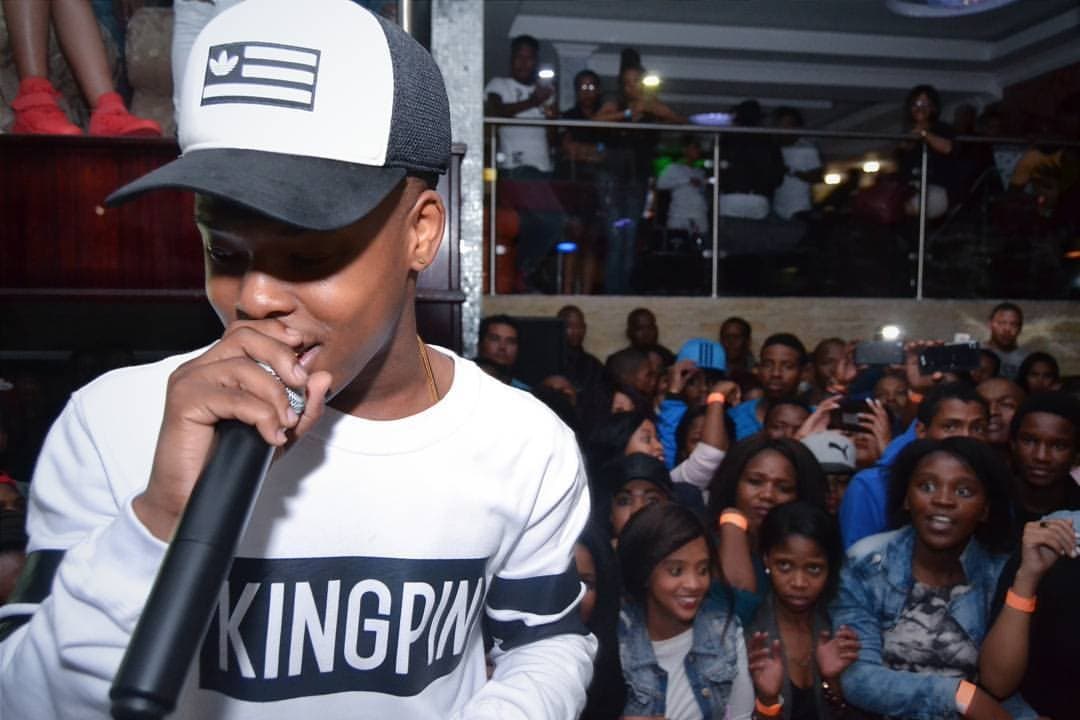 Rapper in a KINGPIN sweater on the mic above the crowd