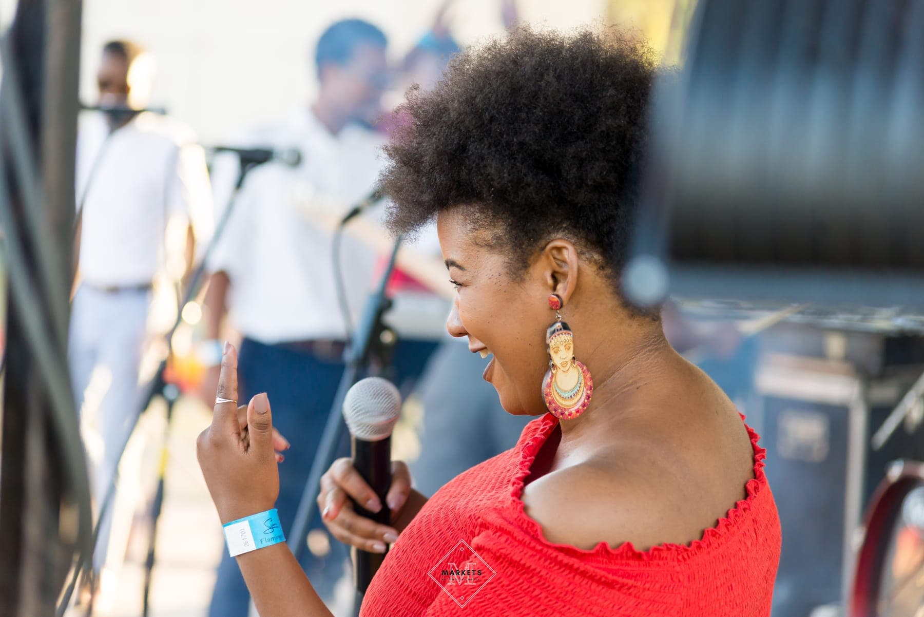 Host in a red top laughing with a microphone