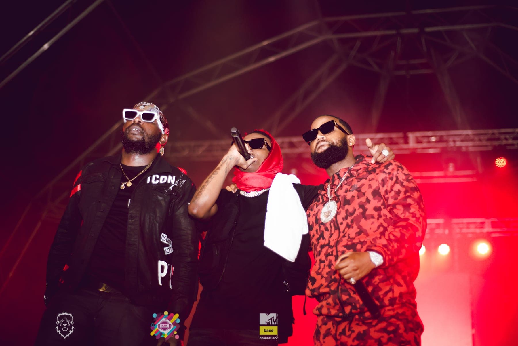 Three performers in red camo and sunglasses on stage