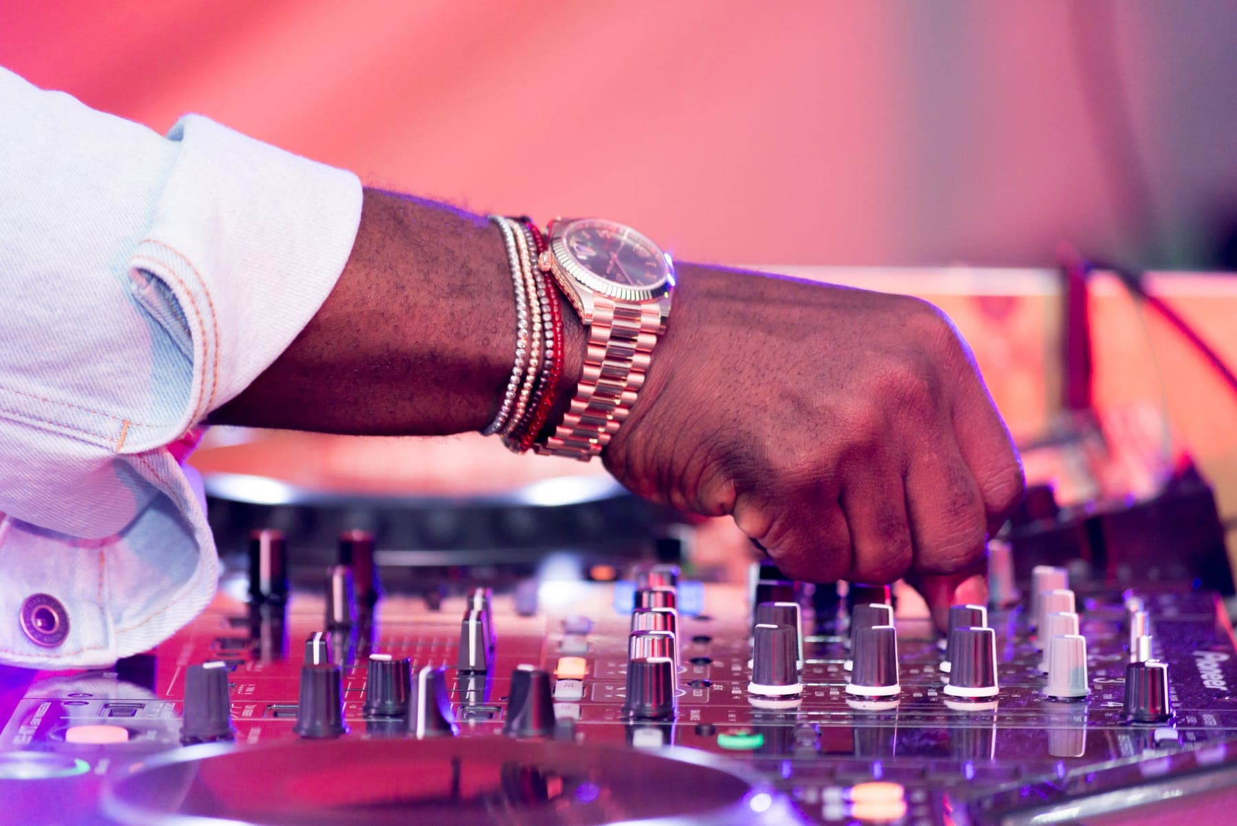 Hand with a gold watch on a DJ mixer