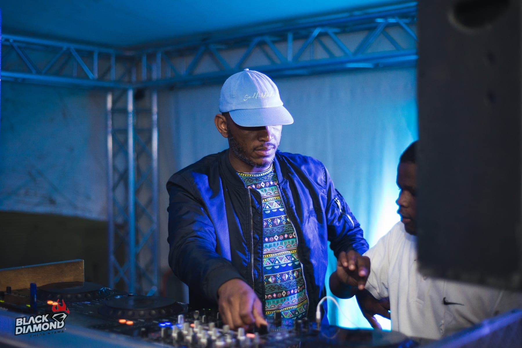 DJ in a white cap and blue bomber at the decks