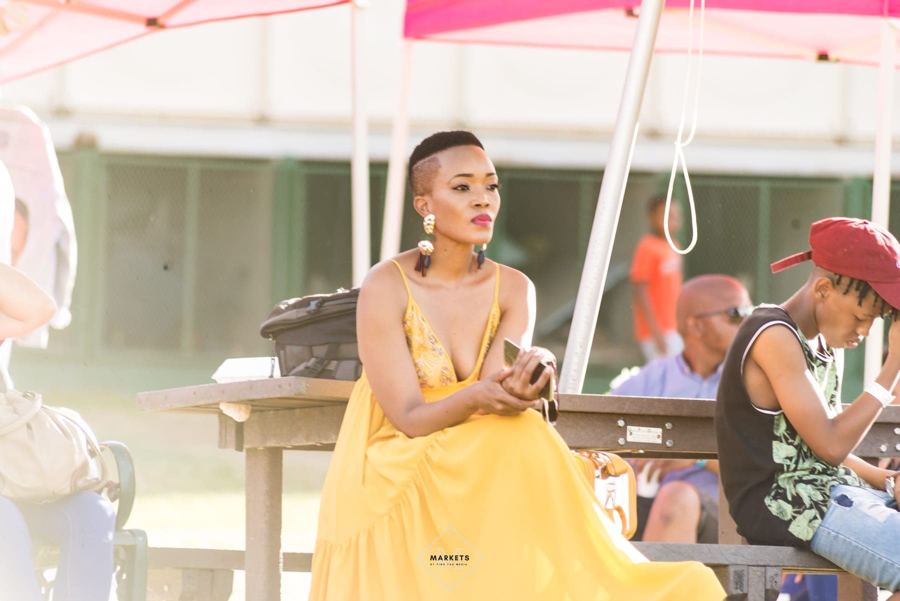 Woman in a yellow dress seated at a daytime festival