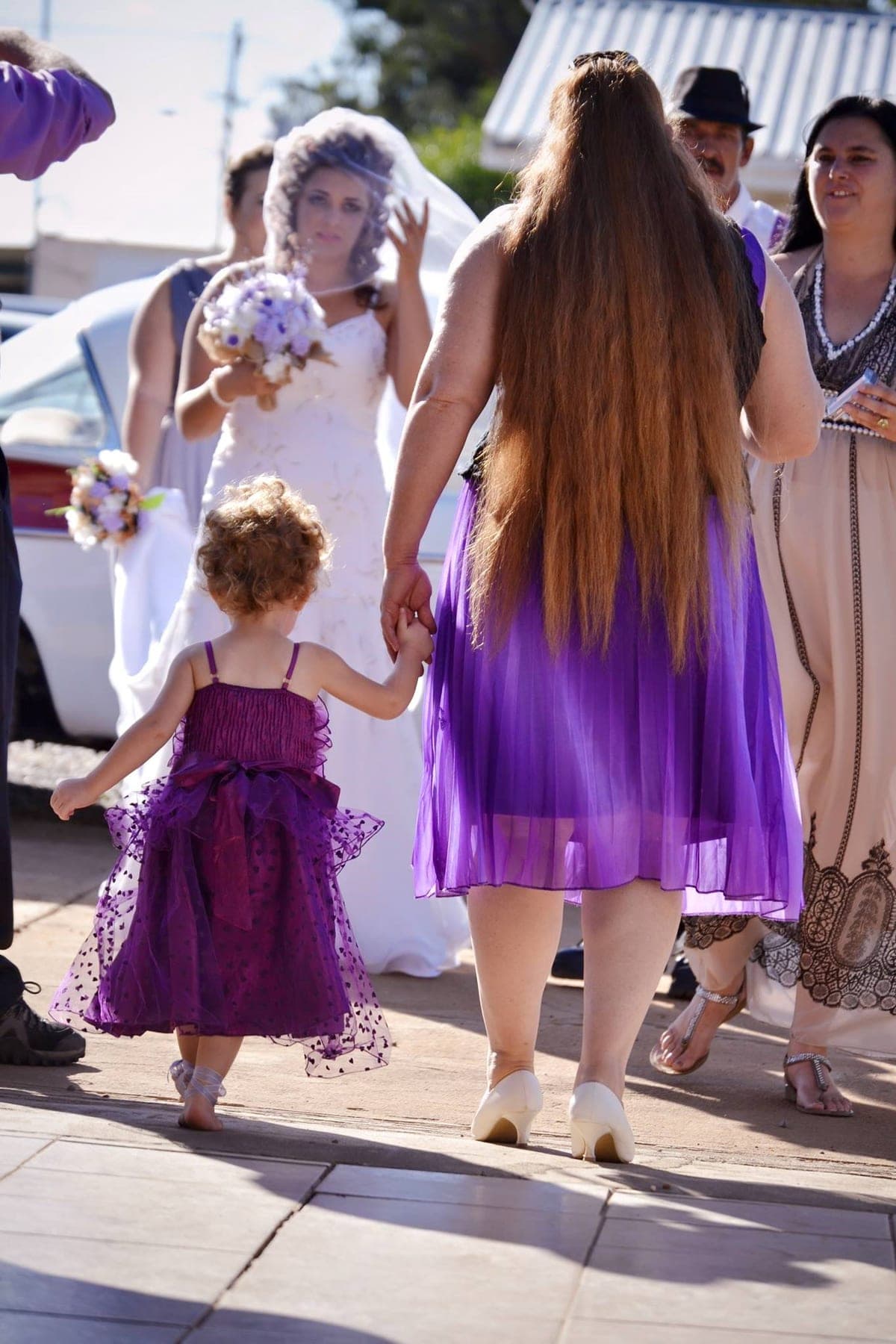 Bride and a flower girl in purple walking in