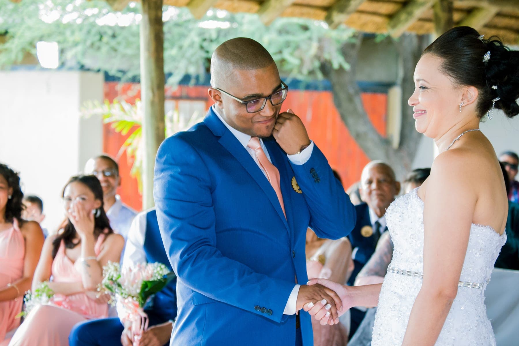 Groom wiping a tear as the bride smiles