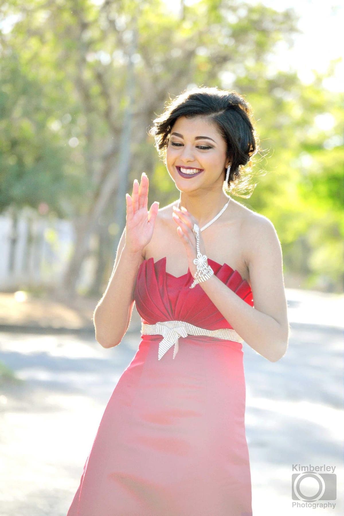 Laughing and clapping in a red strapless dress