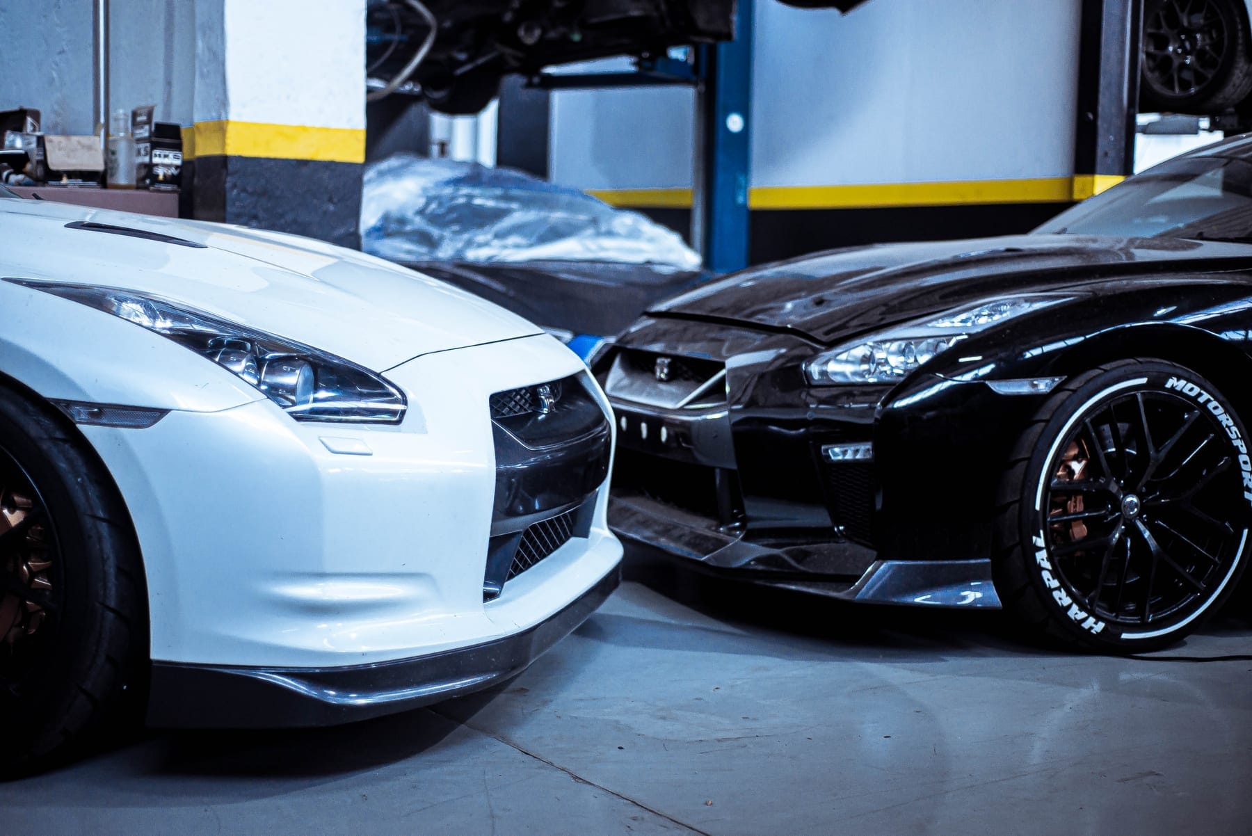 White GT-R and a black coupe side by side in the workshop