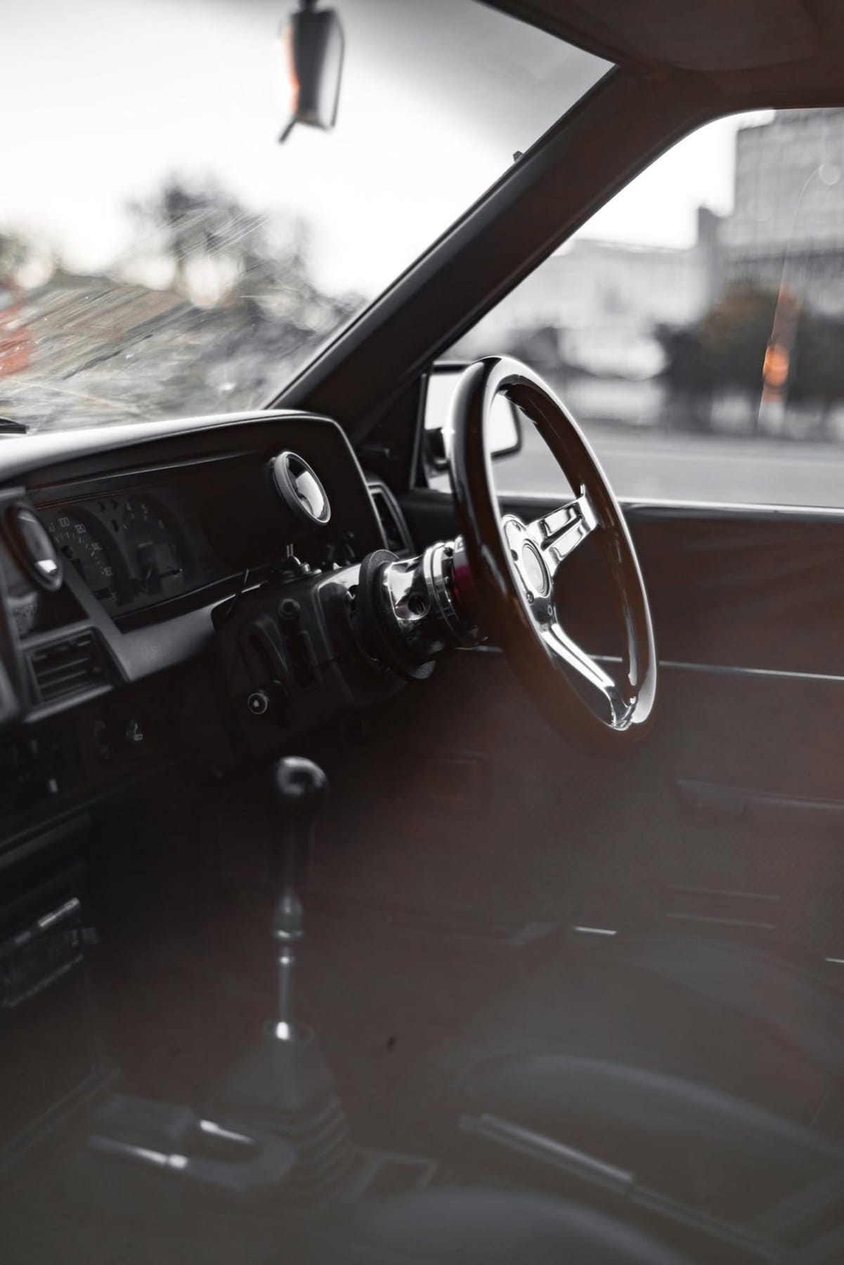 Wooden steering wheel in a classic cabin, the city beyond the glass