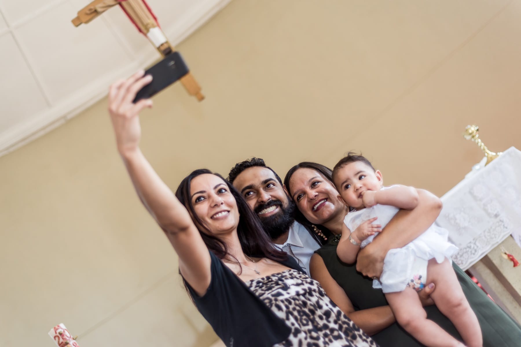 Family selfie by the altar candles at a christening
