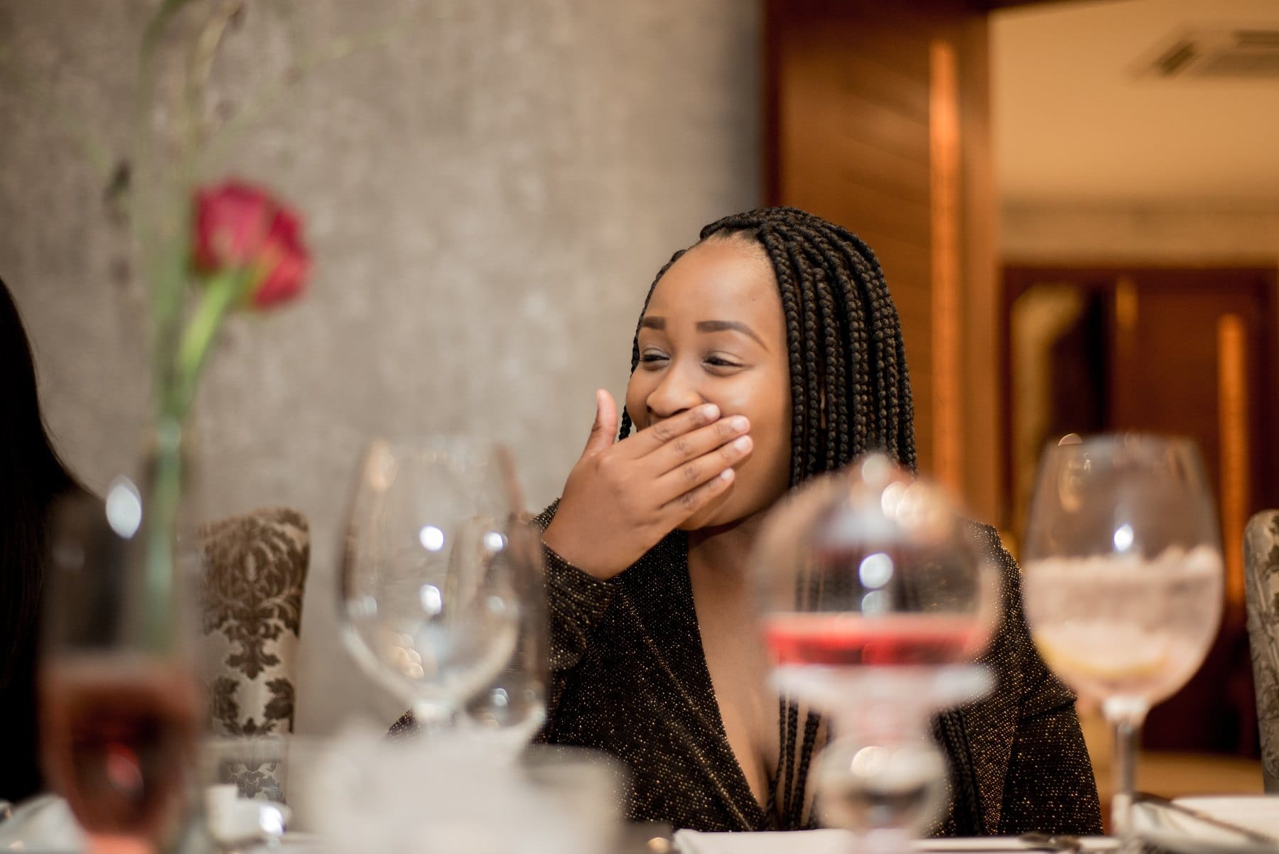 A laugh caught behind a hand at dinner