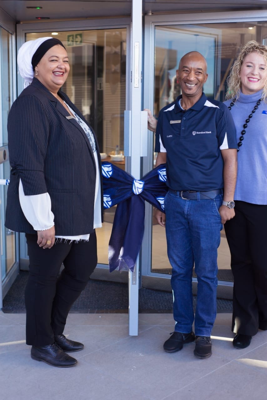 Three of the branch team smiling at the entrance before the opening