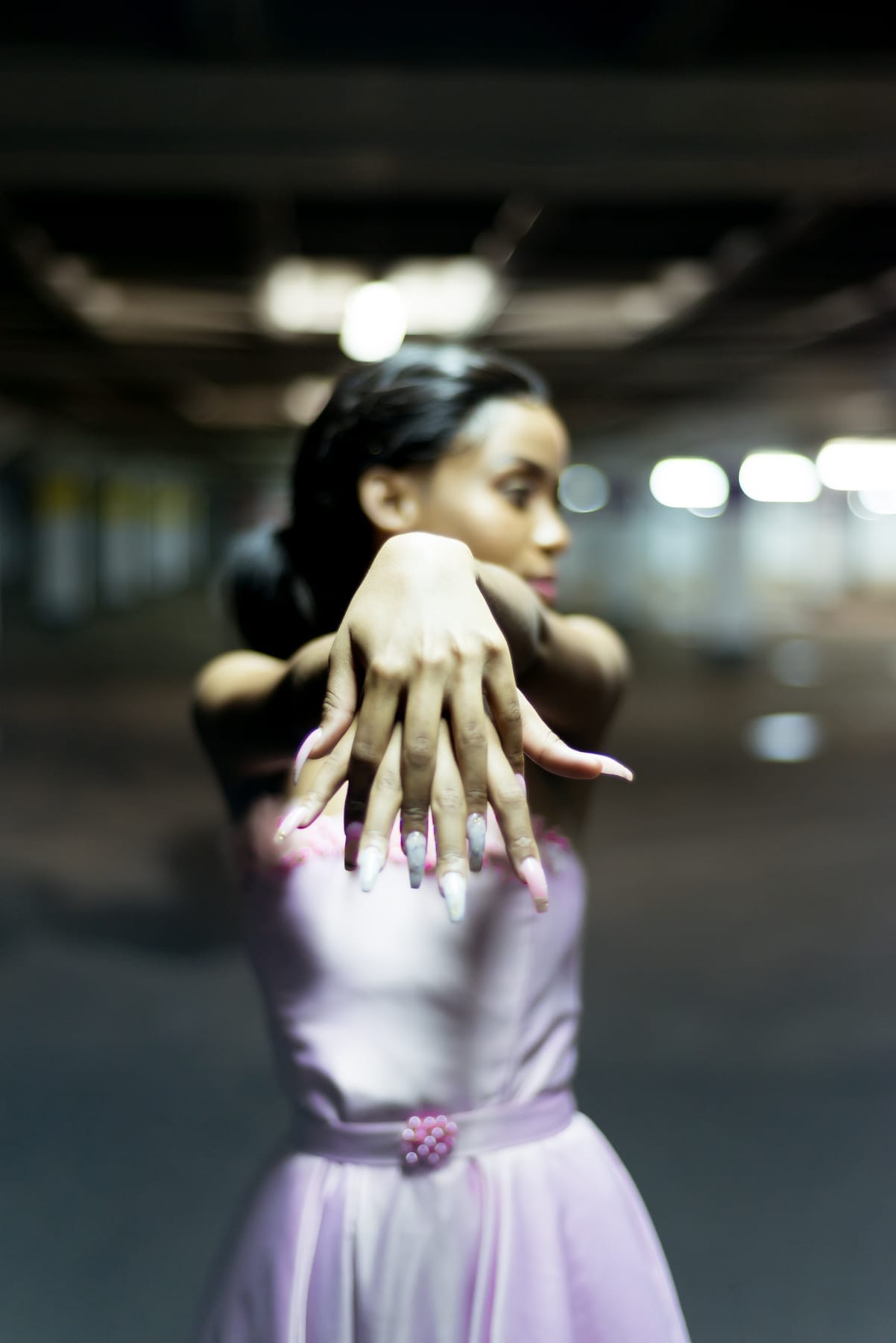 Lilac gown and a raised hand in a parking garage