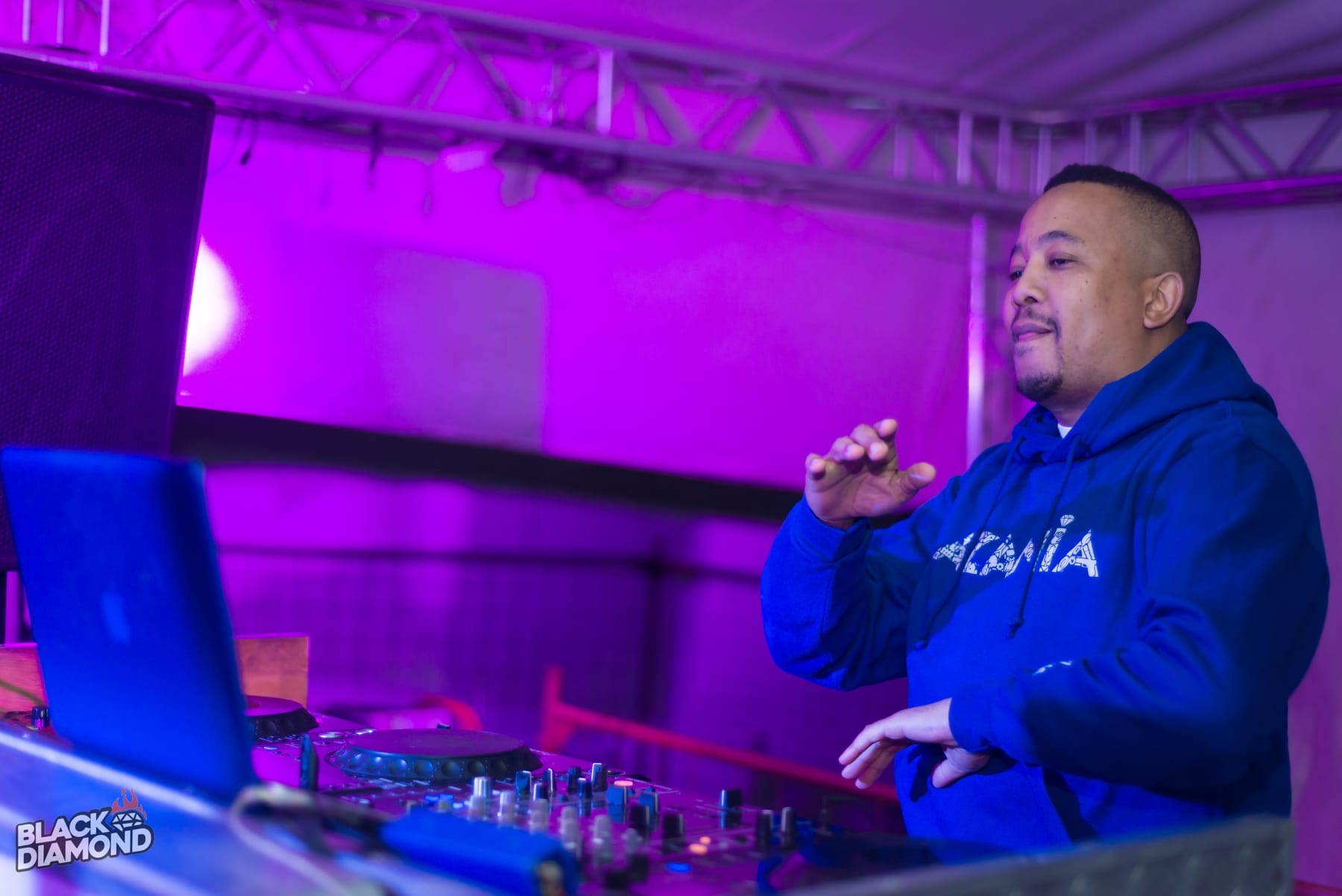 DJ in a blue hoodie at the mixer in a purple wash