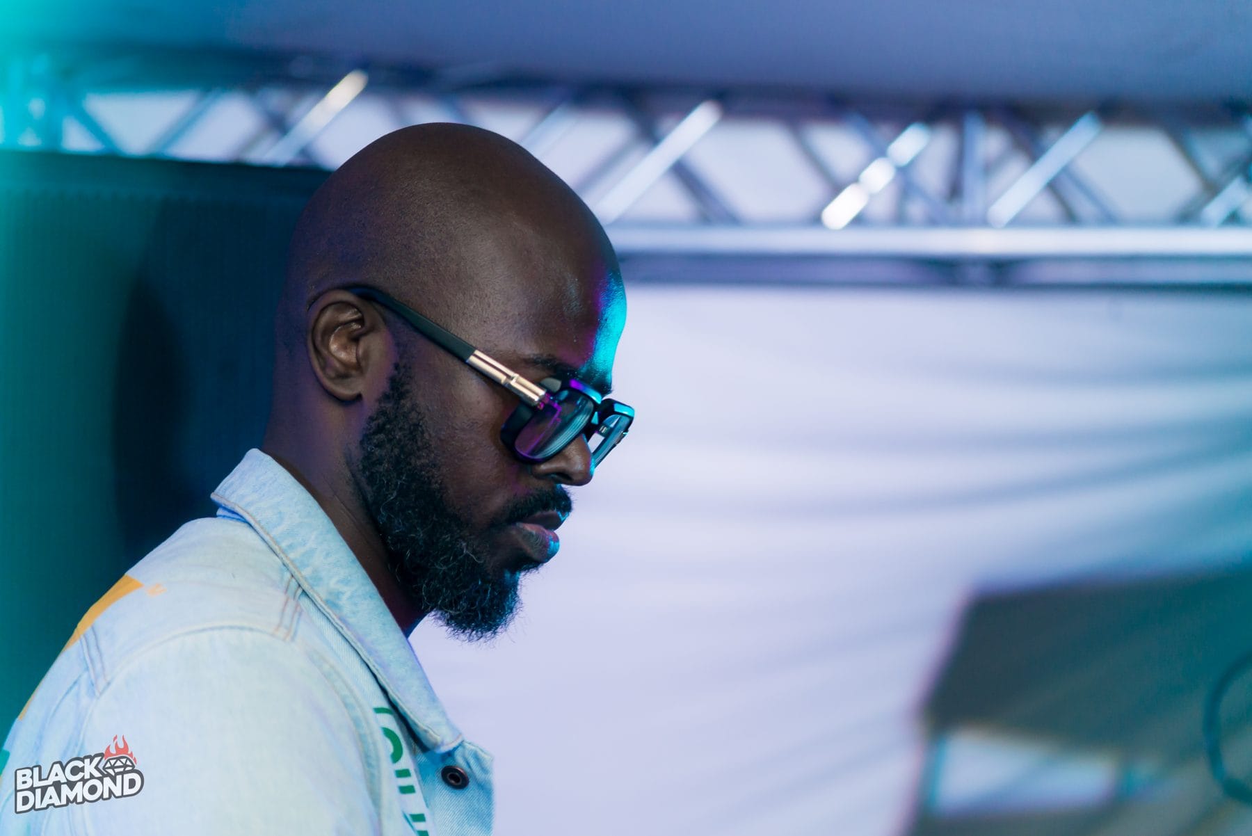 DJ in dark glasses at the decks, lit blue