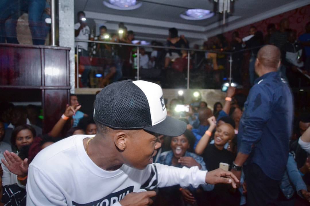 Rapper in a trucker cap reaching into a packed club crowd