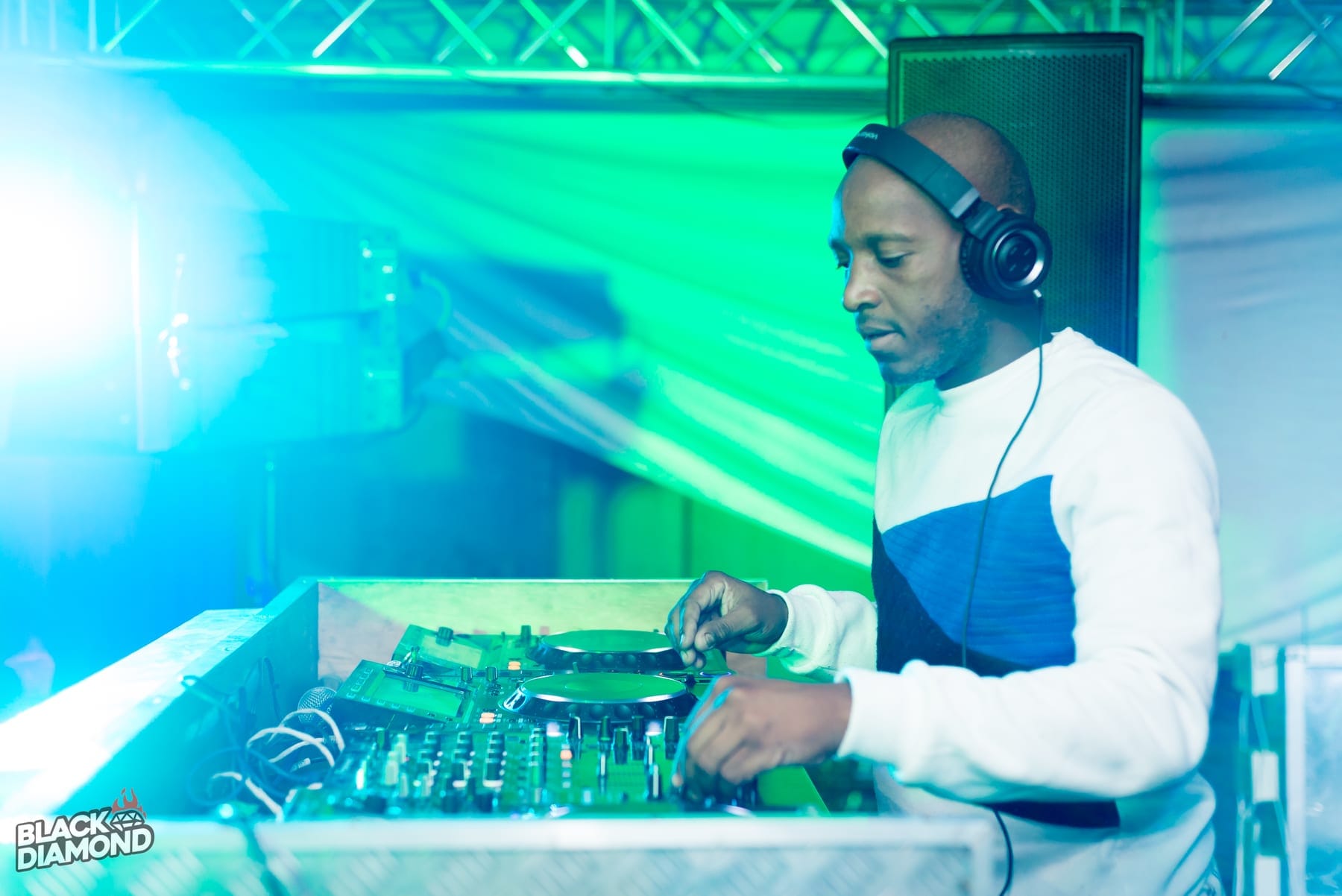 DJ in headphones at the decks under blue beams